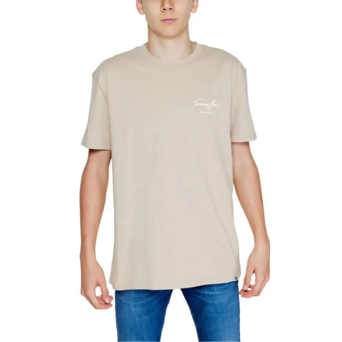 Person wearing a beige t-shirt with a small logo and blue jeans from Tommy Hilfiger Jeans collection