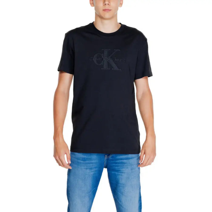 Black Calvin Klein t-shirt with embossed logo worn by person in blue jeans