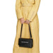 Black Calvin Klein handbag with chain strap showcased in front of a yellow coat