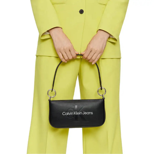 Black Calvin Klein Jeans handbag contrasting with a bright yellow outfit