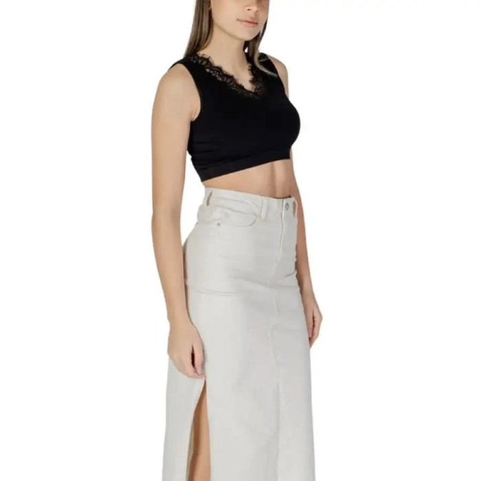 Black sleeveless V-neck crop top with lace trim paired with a white maxi skirt