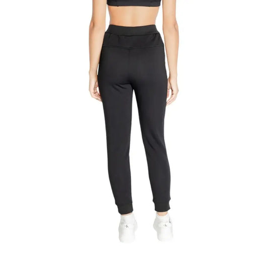 Black high-waisted jogger pants worn by a person from waist down, Calvin Klein Sport