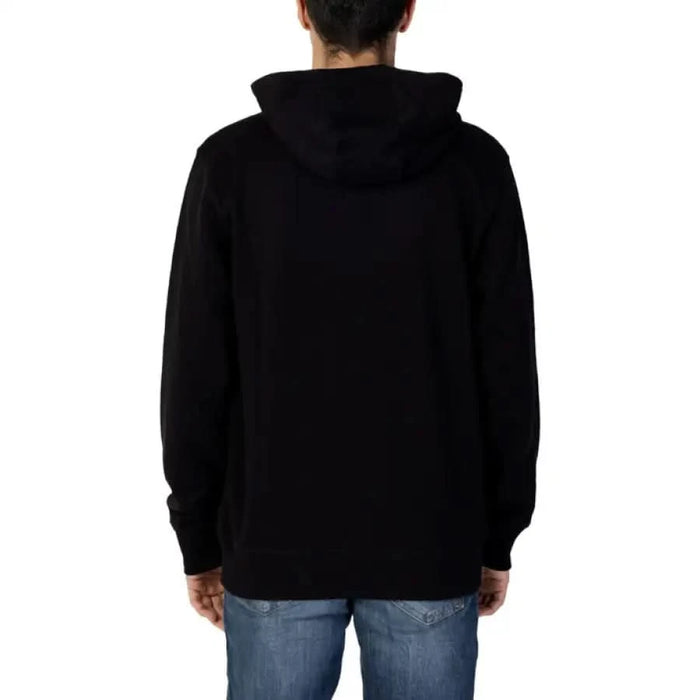 Black hooded sweatshirt by Tommy Hilfiger Jeans, worn by a person facing away from the camera