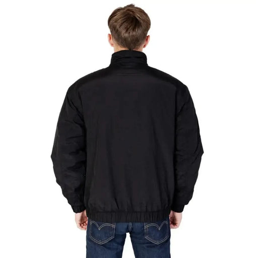 Black jacket viewed from the back with blue jeans on a model wearing Tommy Hilfiger