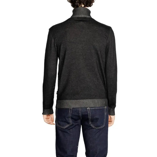 Black knit sweater layered over striped turtleneck paired with dark jeans by Hamaki-ho