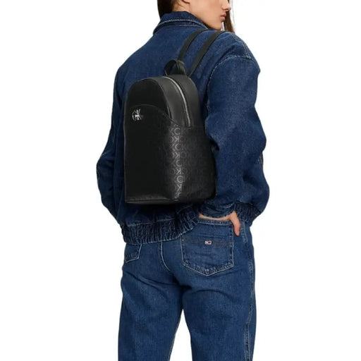 Black leather Calvin Klein Women Bag displayed on a person in denim clothing