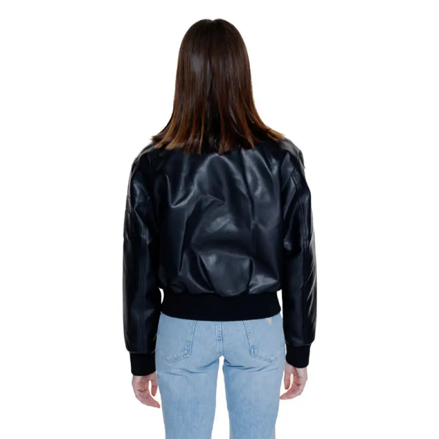 Calvin Klein black leather bomber jacket over light blue jeans, back view