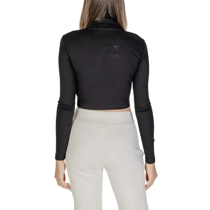 Black long-sleeved cropped turtleneck top paired with white pants from Calvin Klein Jeans