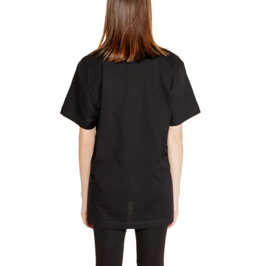 Back view of a person in black oversized Guess Women’s Knitwear t-shirt, brown hair flowing