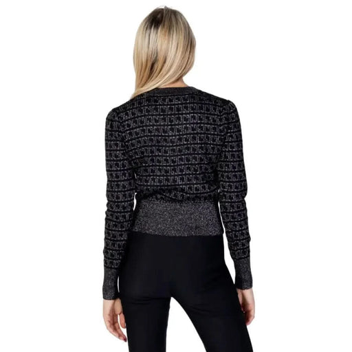 Blonde person wearing Gaudì Jeans black patterned sweater, back view