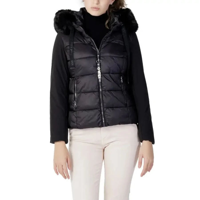 Gaudì Jeans Women’s Black Puffer Vest with Fur-Trimmed Hood over Dark Top and Light Pants