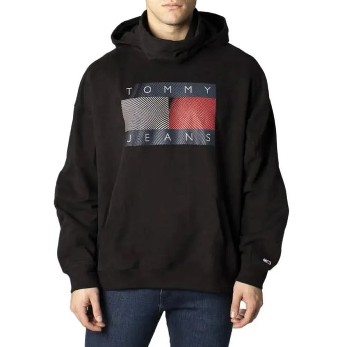 Black Tommy Jeans hoodie with geometric logo in white, gray, and red displayed for men