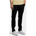 Black trousers by Lyle & Scott styled with white sneakers for men