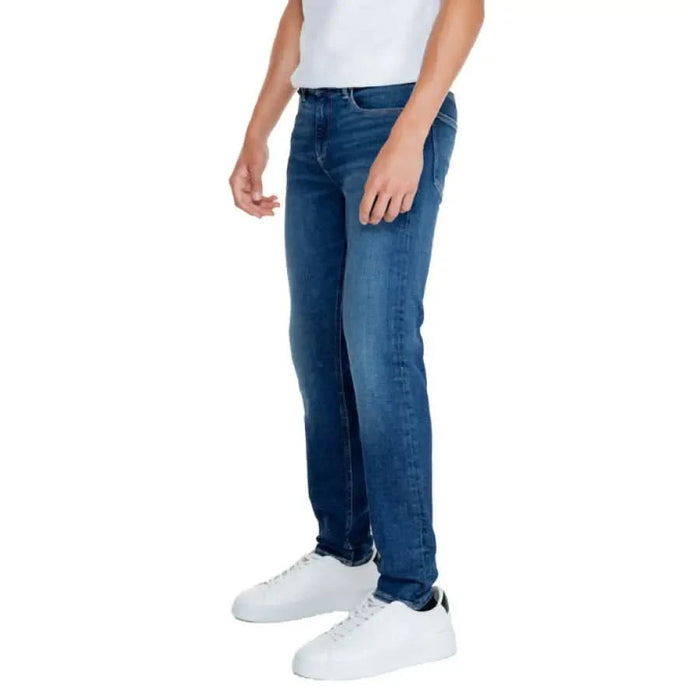 Blue denim jeans paired with white sneakers from Calvin Klein Jeans for men