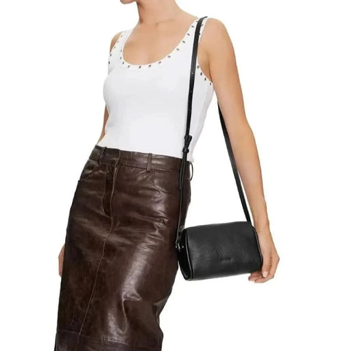 Brown leather pencil skirt styled with a white sleeveless top and black shoulder bag