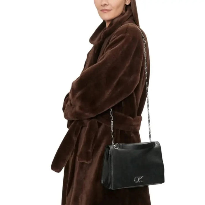 Brown plush faux fur coat with belt and black shoulder bag by Calvin Klein