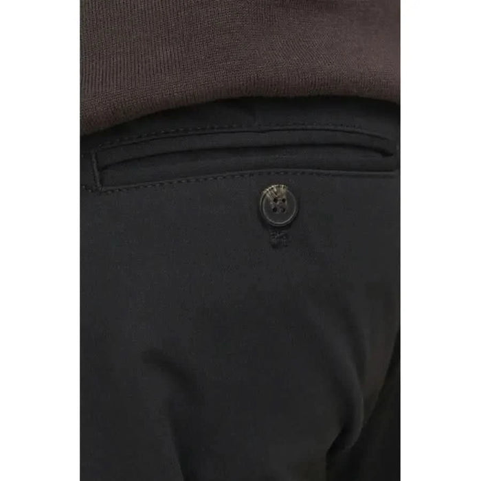 Button on a black fabric pocket of Jack & Jones Men Trousers