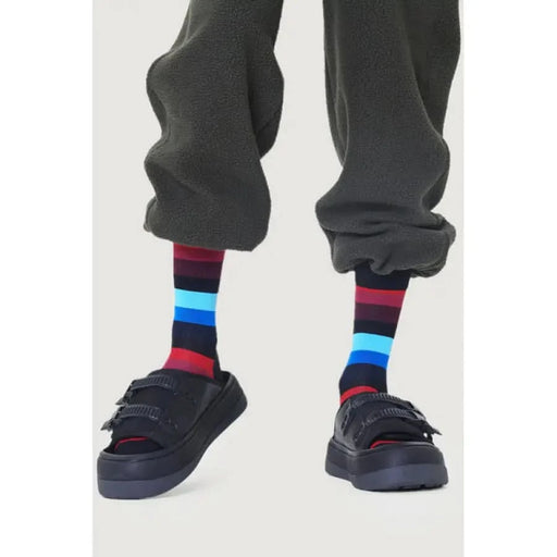 Colorful striped socks paired with black sneakers and dark pants from Happy Socks