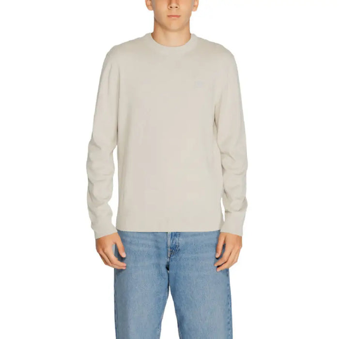 Cream-colored long-sleeved sweater paired with blue jeans from Boss Men Knitwear