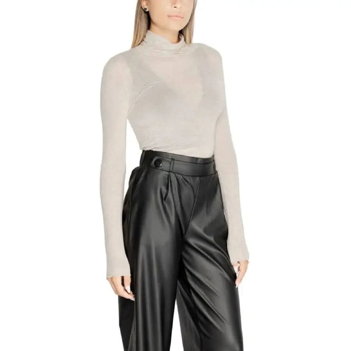 High-waisted black leather pants with cream turtleneck sweater for stylish pairing