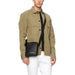 Khaki button-up shirt with pockets over white pants and a black Calvin Klein bag