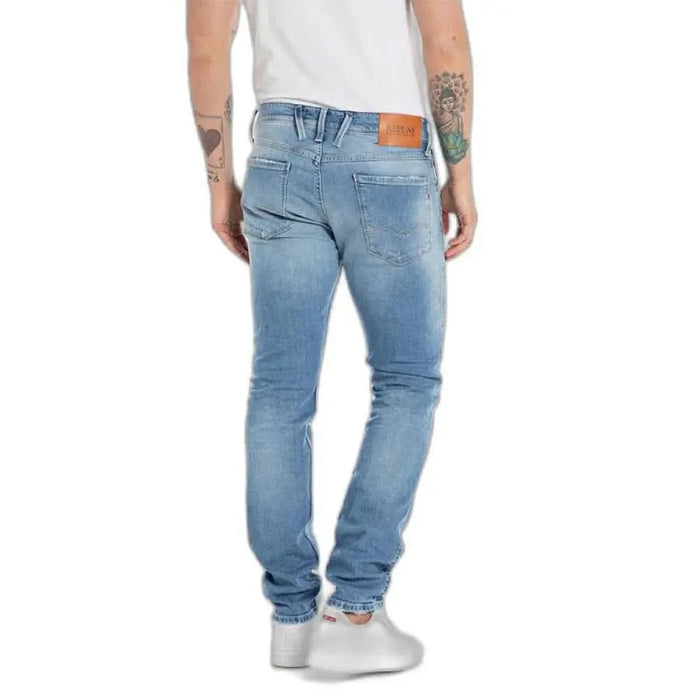 Light blue denim jeans modeled by a person with arm tattoos from Replay Men Jeans