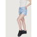 Light blue frayed denim shorts by Tommy Hilfiger, paired with a white top and black sneakers