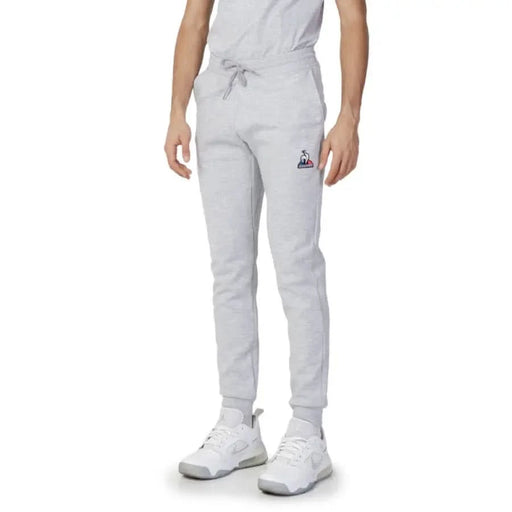 Le Coq Sportif Men’s light gray sweatpants with a logo on the thigh, paired with white sneakers