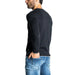 Man in black long-sleeved shirt and blue jeans showcasing Armani Exchange knitwear