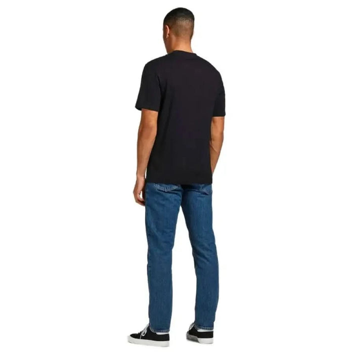 Man in Jack & Jones black t-shirt and blue jeans, viewed from behind