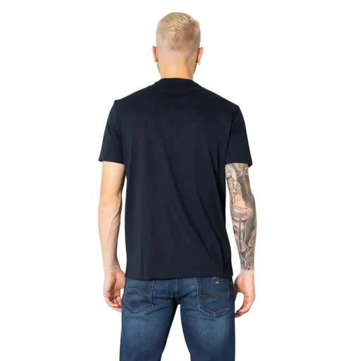 Man in navy blue Armani Exchange T-shirt and jeans, showcasing a tattoo sleeve on his right arm