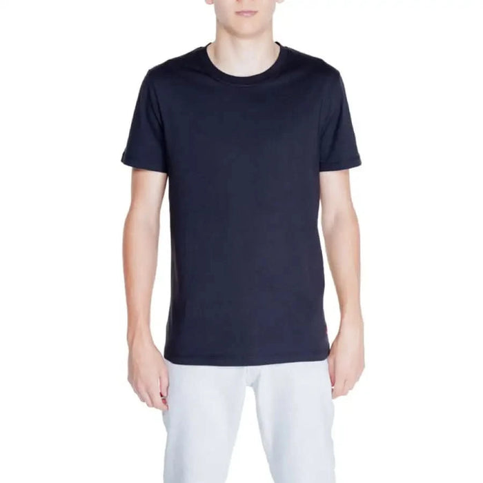 Peuterey Men T-Shirt in navy blue worn by model in white pants