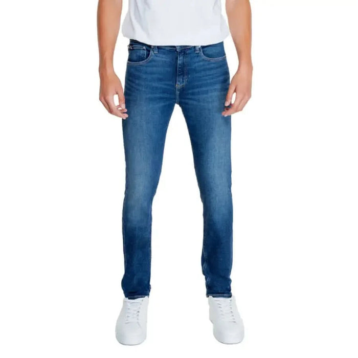 Blue denim jeans worn by a person, featuring Calvin Klein Jeans branding