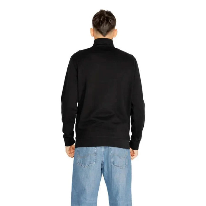 Back view of man wearing a black turtleneck sweater and blue jeans Boss Men Sweatshirts