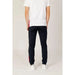 Person in Le Coq Sportif white t-shirt and navy blue pants with red stripes, rear view