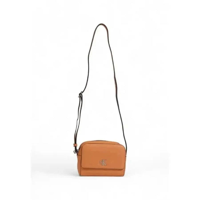 Tan leather crossbody bag with long strap and metal logo emblem by Calvin Klein