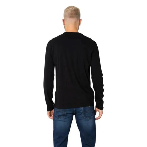 Back view of person in Armani Exchange black long-sleeved shirt and blue jeans