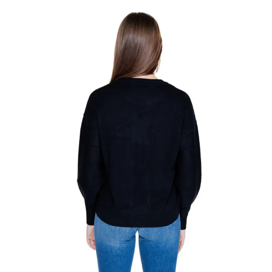 Back view of a woman in a black sweater and blue jeans, Guess Women Knitwear