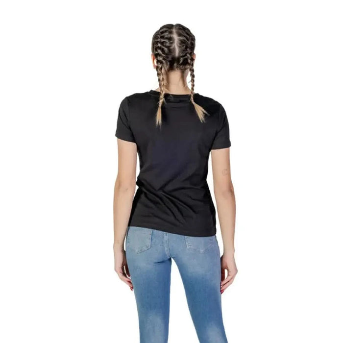 Back view of a person in Guess Women Black Round Neck Short T-Shirt and blue jeans