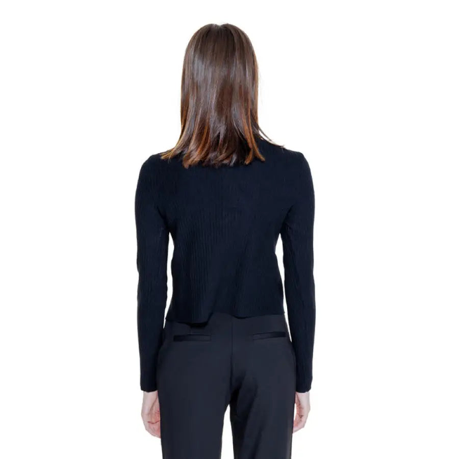 Back view of a person in Morgan De Toi Women Knitwear black long-sleeved top and dark pants