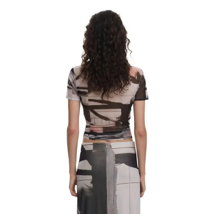 Back view of a woman with curly hair in a geometric patterned dress by Desigual