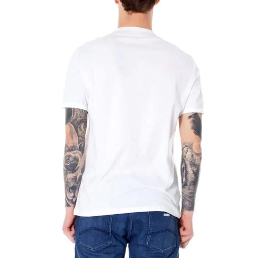 Back view of person in white Armani Exchange T-shirt, blue jeans, tattoos on both arms