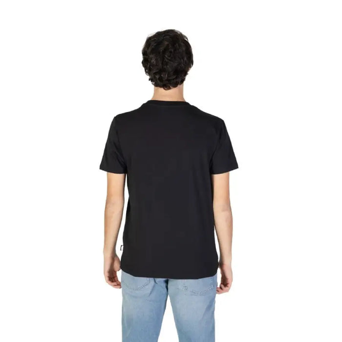 Back view of man in black T-shirt and light blue jeans showcasing Moschino Underwear