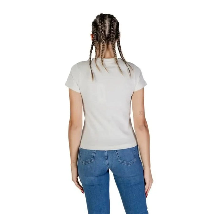 Back view of a person in a Guess Active white t-shirt and blue jeans with braided hair