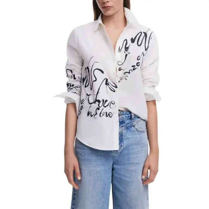 White button-down shirt with black swirl designs paired with light blue jeans for women