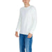 White long-sleeved crewneck sweater paired with blue jeans in Calvin Klein Jeans collection