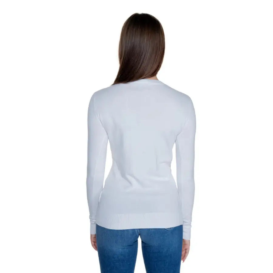 Back view of a long-haired woman wearing Guess Women’s Knitwear white long-sleeved sweater