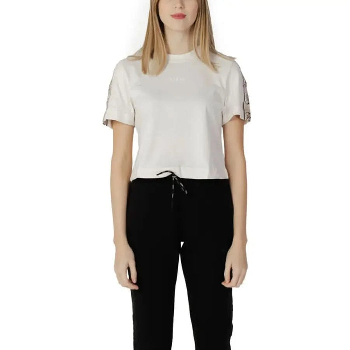 White t-shirt with decorative sleeves styled with black pants from Guess Active Women