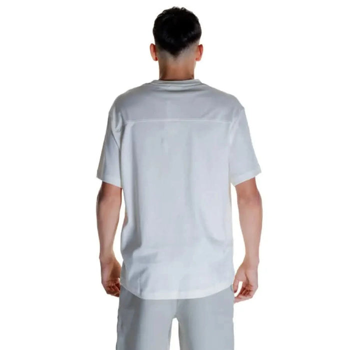 Back view of a person wearing a white Calvin Klein Men T-Shirt by Calvin Klein