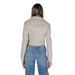 Woman in beige Guess blazer with side zip fastening and blue jeans